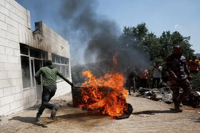 A Palestinian man runs near a burning object, after an attack by Israeli settlers, near Ramallah, in the Israeli-occupied West Bank on June 21, 2023. (Photo by Mohamad Torokman/Reuters)