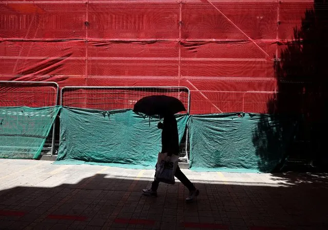 A man shelters from the sun with an umbrella during a heatwave in Nicosia, Cyprus on July 15, 2023. (Photo by Yiannis Kourtoglou/Reuters)