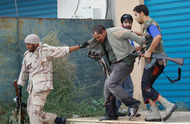 A Gaddafi loyalist (C) is captured by anti-Gaddafi fighters during fighting in the centre of Sirte, Libya  October 13, 2011. (Photo by Thaier al-Sudani/Reuters)