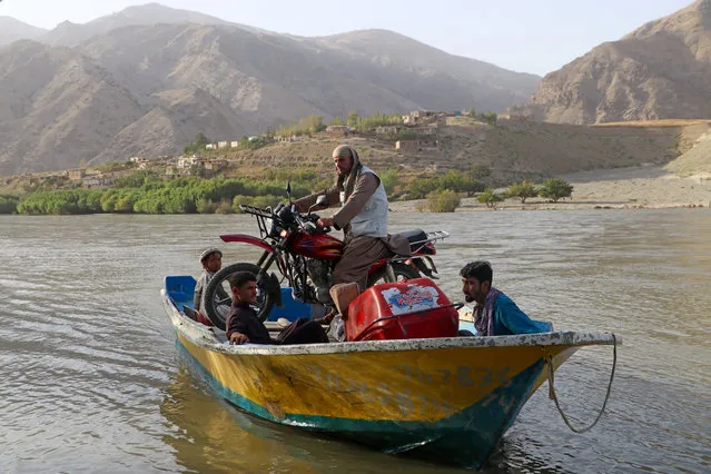 Afghan men ferry a motorcycle on a boat across the Kokcha river on the outskirts of Fayzabad district of Badakhshan province on August 20, 2023. (Photo by Omer Abrar/AFP Photo)