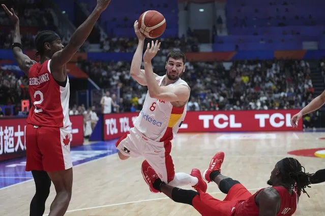 Spain guard Dario Brizuela (8) leaps as he drives against Canada guards Shai Gilgeous-Alexander (2) and Luguentz Dort (0) during the Basketball World Cup second round match between Spain and Canada at the Indonesia Arena stadium in Jakarta, Indonesia, Sunday, September 3, 2023. (Photo by Tatan Syuflana/AP Photo)