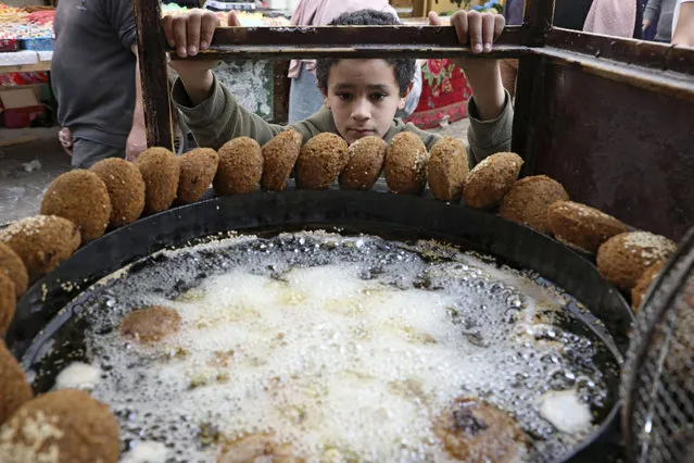 A Palestinian boy waits for a batch of falafel at a vendor in the city of Hebron in the occupied West Bank, during the Muslim holy fasting month of Ramadan on April 18, 2021. (Photo by Hazem Bader/AFP Photo)
