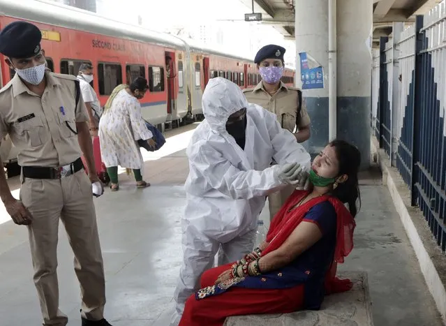 A health worker collects swab sample of traveler to test for COVID-19 at train station in Mumbai, India, Monday, May 24,2020. (Photo by Rajanish Kakade/AP Photo)