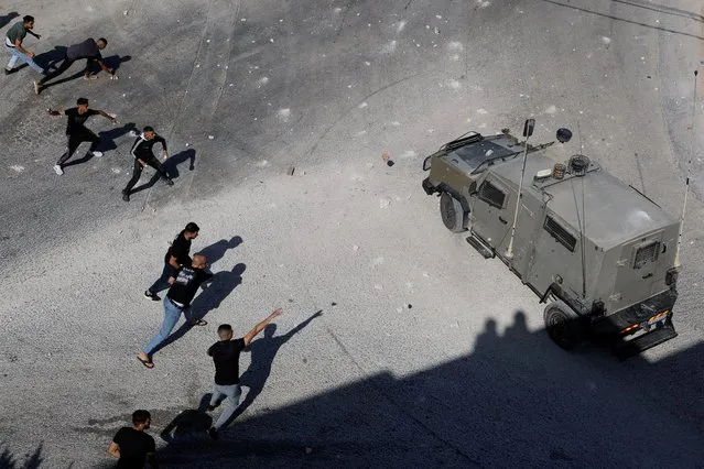 Palestinians throw objects next to an Israeli military vehicle during a raid near Tubas in the Israeli-occupied West Bank on September 1, 2023. (Photo by Raneen Sawafta/Reuters)