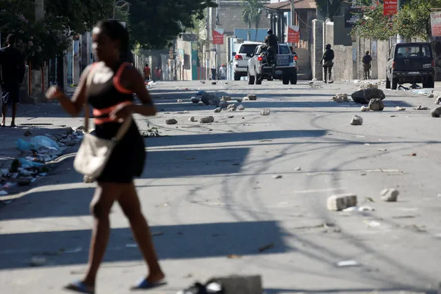 A woman walks in a street as Haitian National Police officers patrol after a march in Port-au-Prince, Haiti on October 17, 2018. (Photo by Andres Martinez Casares/Reuters)