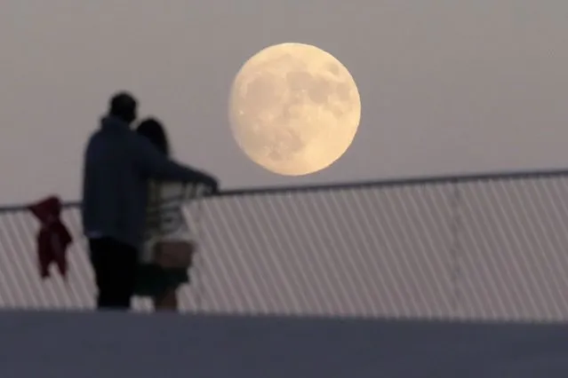 A couple standing on the roof of Lisbon's Museum of Art, Architecture and Technology watch a nearly full moon rise, Tuesday, August 29, 2023. August 30 will see the month's second supermoon, when a full moon appears a little bigger and brighter thanks to its slightly closer position to Earth. (Photo by Armando Franca/AP Photo)