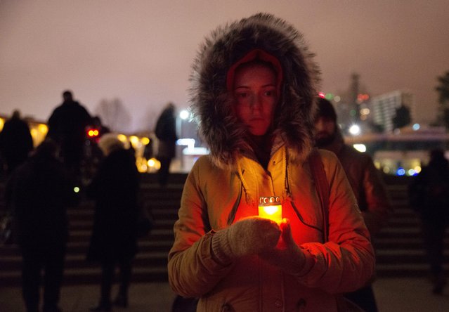 A Russian woman holds a candle in memory of victims of  the Defence Ministry's Tu-154 plane crash near Sochi, Russia, 25 December 2016. Tupolev-154 Russian airplane had 93 people on board, 8 crew members, 9 Russian TV journalists and the others mostly members of Alexandrov Song and Dance ensemble. The plane headed to Syria to support  Russian military airbase servicemen. (Photo by Yevgeny Reutov/EPA)