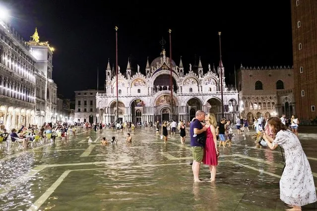 People walk in a flooded St. Mark's Square during an exceptional high water in Venice, Italy on August 8, 2021. (Photo by Manuel Silvestri/Reuters)
