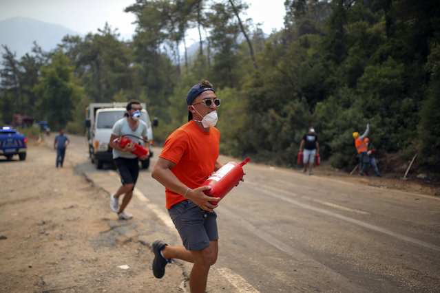 A Turkish volunteer runs as they head to fight wildfires in Turgut village, near tourist resort of Marmaris, Mugla, Turkey, Wednesday, August 4, 2021. (Photo by Emre Tazegul/AP Photo)