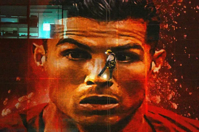 A worker installs a large picture of Portugal's forward Cristiano Ronaldo on a building in Doha on November 20, 2022, during the opening day of the Qatar 2022 World Cup football tournament (Photo by Gabriel Bouys/AFP Photo)