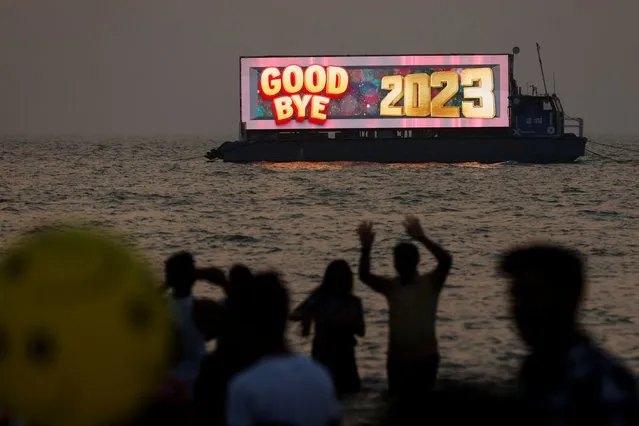 People watch the last sunset of the year from a beach on New Year's eve in Mumbai, India on December 31, 2023. (Photo by Francis Mascarenhas/Reuters)