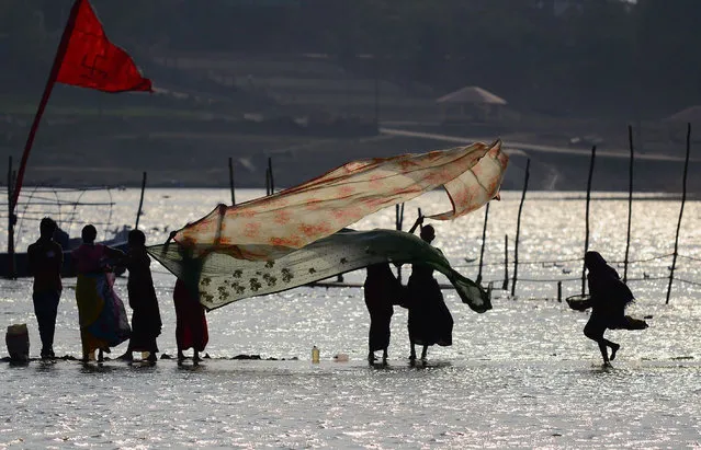 Indian women dry their saris after taking a dip at Sangam, the confluence of the Rivers Ganges, Yamuna and mythical Saraswati, in Allahabad on March 6, 2016. (Photo by Sanjay Kanojia/AFP Photo)