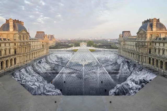 This handout picture released and taken on March 30, 2019 by JR-ART.net shows the huge collage by French artist JR in the courtyard of the Louvre, a project unveiled to mark the 30th birthday of the Louvre's glass pyramid in Paris. Some 400 volunteers working in teams of 50 spent four days pasting strips of printed paper on the cobbles of the courtyard, creating a giant patchwork around the pyramid. Hated by many Parisians when it was unveiled 30 years ago on March 29, Chinese-American architect I. M. Pei's creation has wormed its way into their hearts and is now revered like one of the Louvre's greatest treasures. (Photo by Handout/JR-ART.net/AFP Photo)
