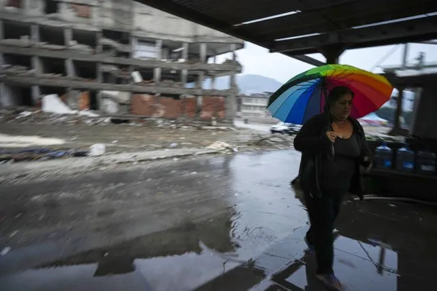 A woman holding an umbrella walks amid destroyed buildings in Antakya, southern Turkey, Friday, January 12, 2024. A year after a powerful earthquake struck on Feb. 6, 2023, many in the stricken region are struggling to rebuild lives. (Photo by Khalil Hamra/AP Photo)