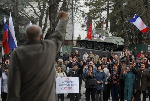 Pro-Russia demonstrators rally at the local parliament building, with a monument of World War II in the background, in Crimea's capital Simferopol, Ukraine, Thursday, March 6, 2014. A poster reads “Kiev, Stop Crime at Home”. (Photo by Sergei Grits/AP Photo)