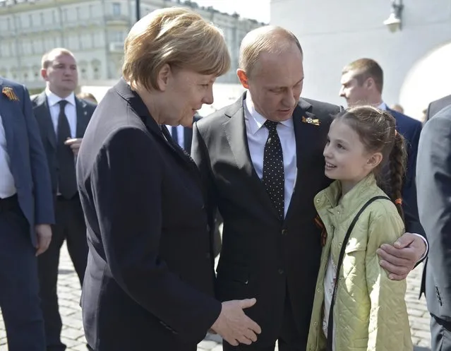 Russian President Vladimir Putin (C) and German Chancellor Angela Merkel (L) talk to a girl after attending a wreath-laying ceremony at the Tomb of the Unknown Soldier by the Kremlin walls in Moscow, Russia, May 10, 2015. Tanks and troops paraded across Moscow's Red Square on May 9 to mark the 70th anniversary of victory over Nazi Germany, an event boycotted by Western leaders over Russia's role in the Ukraine crisis. (Photo by Reuters/Host Photo Agency/RIA Novosti)