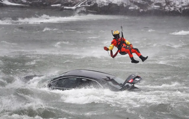 A U.S. Coast Guard diver is lowered from a hovering helicopter to pull a body from a submerged vehicle stuck in rushing rapids just yards from the brink of Niagara Falls, Wednesday, December 8, 2021, in Niagara Falls, N.Y. (Photo by Sharon Cantillon/The Buffalo News via AP Photo)