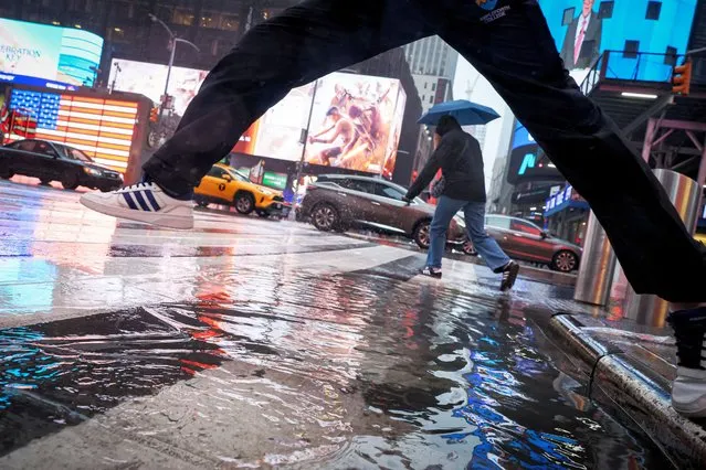 People walk through wind and rain during a nor'easter storm in Times Square in New York City on April 3, 2024. (Photo by Brendan McDermid/Reuters)