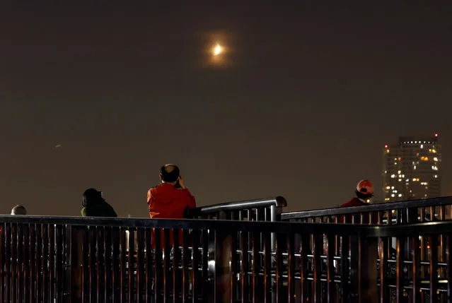 People observe a partial lunar eclipse in Tokyo, Japan on November 19, 2021. (Photo by Issei Kato/Reuters)