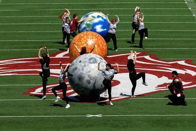 People dance next to representations of the earth, sun and moon at Saluki Stadium, in Carbondale, Illinois on April 8, 2024. (Photo by Evelyn Hockstein/Reuters)