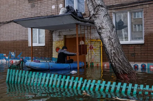 A man sits in an inflatable boat in a flooded residential area in Orsk, Orenburg region, Russia, on April 13, 2024. (Photo by Maxim Shemetov/Reuters)