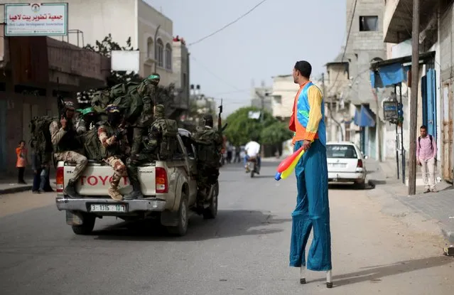 Palestinian Majed Kalluob, 24, walks with stilts as he looks at Hamas militants riding a pickup truck on a street in the northern Gaza Strip April 8, 2016. (Photo by Ibraheem Abu Mustafa/Reuters)