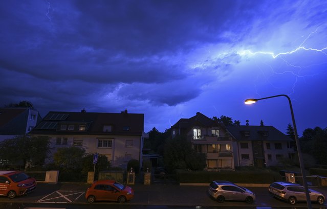 In this shot with slow shutter speed, lightning discharges in the evening sky during a heavy thunderstorm over the houses in the district of Sachsenhausen, Frankfurt/Main, Germany Wednesday, August 16, 2023. Heavy rain in parts of Germany caused flooding and led to dozens of flight cancelations at Frankfurt Airport, the country's busiest and a major European hub, authorities said Thursday. (Photo by Arne Dedert/dpa via AP Photo)