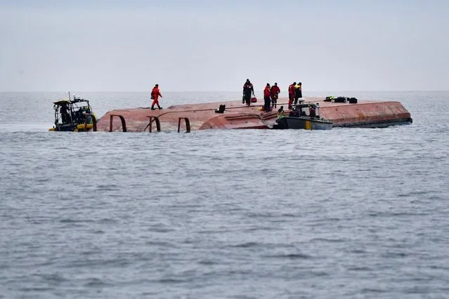 Divers and members of a sea rescue team work on the capsized Danish cargo ship Karin Hoej which collided with the British cargo ship Scot Carrier on the Baltic Sea between the Swedish city of Ystad and the Danish island of Bornholm, on December 13, 2021. Two people were missing after the two cargo ships collided in the early morning hours, the Swedish Maritime Administration said. (Photo by Johan Nilsson/TT News Agency/AFP Photo)