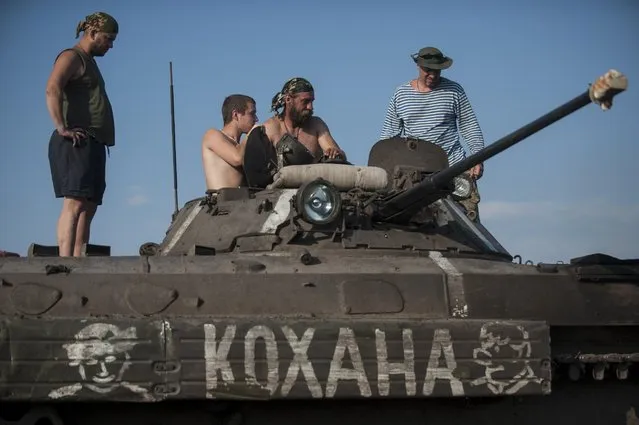 In this photo taken Monday, June 22, 2015, Ukrainian servicemen from the Kiev-2 volunteer battalion talk atop an armored vehicle with a word on it saying “my love” in Ukrainian at the frontline in the village of Krymske, east Ukraine. (Photo by Evgeniy Maloletka/AP Photo)