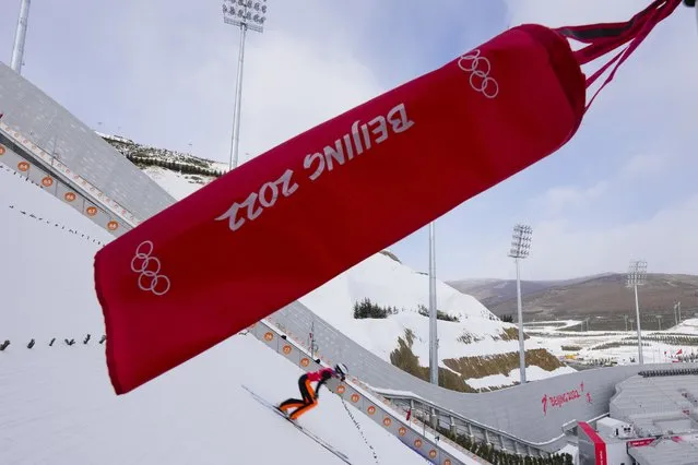 A competitor passes a flad indicating wind direction during a men's normal hill ski jumping training session at the 2022 Winter Olympics, Friday, February 4, 2022, in Zhangjiakou, China. (Photo by Andrew Medichini/AP Photo)