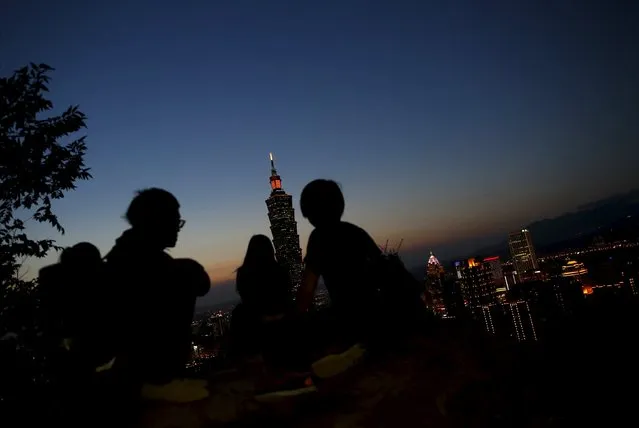 People react on the top of a rock as Taiwan's landmark building is seen during sunset in Taipei, Taiwan April 19, 2016. (Photo by Tyrone Siu/Reuters)