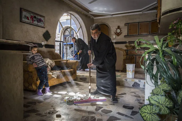 A family starts to clean up after the home they had only just returned to was damaged by a car bomb used by Islamic State militants in the Jidedeh neighborhood of western Mosul, Iraq, March 25, 2017. Even with fighting all around them, many Mosul residents have heeded the government's requests to stay home as long they can hold out. Most are in dire need of food and water. (Photo by Ivor Prickett/The New York Times)