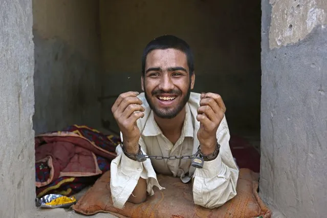 Muhibullah, 20, a drug addict, is handcuffed in a cell in his 40-day incarceration at the Mia Ali Baba shrine in Jalalabad, Afghanistan, Thursday, May 1, 2014. It is believed locally that 40 days of chaining to a wall with a restricted diet at the 300-year old shrine can cure the mentally ill, drug addicts and those possessed by spirits. If a shrine keeper decides their situation is improving, they may be unchained for a few minutes. (Photo by Rahmat Gul/AP Photo)