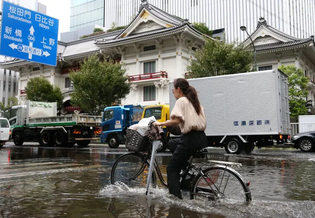 A woman cycles through a flooded area in Tokyo on September 9, 2019. A powerful typhoon with potentially record winds and rain battered the Tokyo region on September 9, sparking evacuation warnings to tens of thousands, widespread blackouts and transport disruption. (Photo by JIJI Press/AFP Photo)