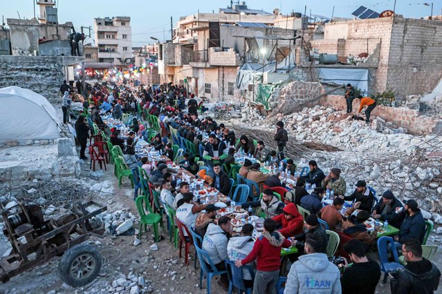 Locals affected by the February 6 earthquake attend a mass “Iftar” fast-breaking dinner in the town of Atareb in the rebel-held western countryside of Aleppo province, on March 31, 2023 at the end of the fasting day during the Muslim holy month of Ramadan. (Photo by Aaref Watad/AFP Photo)