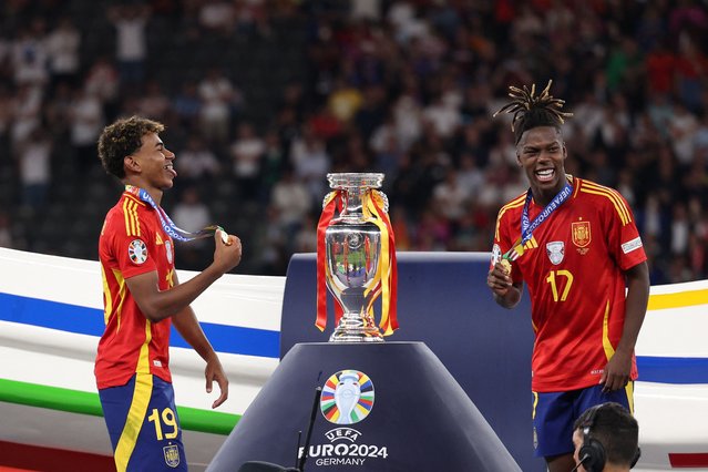 Spain's forward #19 Lamine Yamal (L) and Spain's midfielder #17 Nico Williams celebrate on the podium after winning the UEFA Euro 2024 final football match between Spain and England at the Olympiastadion in Berlin on July 14, 2024. (Photo by Adrian Dennis/AFP Photo)