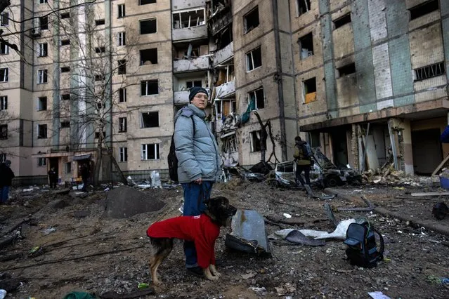 A resident stands with her dog next to a destroyed building after a bombing in Satoya neighborhood in Kyiv, Ukraine, Sunday, March 20, 2022. (Photo by Rodrigo Abd/AP Photo)
