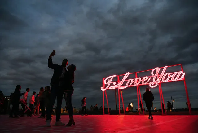 A couple takes a selfie in front of the the art installation entitled, “I Love You” on opening night along the Alexandria waterfront  on Friday March 25, 2022 in Alexandria, VA. The installation was created by R&R Studios. It is on display till November 2022. (Photo by Matt McClain/The Washington Post)