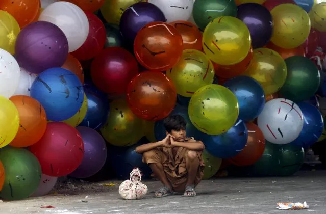 A boy sits next to bunch of balloons for sale on the first day of Eid-al-Fitr which marks the end of the holy fasting month of Ramadan in Karachi, Pakistan July 18, 2015. (Photo by Athar Hussain/Reuters)
