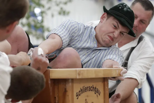 A man dressed in traditional clothes tries to pull his opponent over the table at the 40th Alpine Country Championships in Fingerhakeln_finger wrestling_ in Woernsmuehl, Germany, Thursday, May 25, 2017. (Photo by Matthias Schrader/AP Photo)