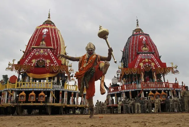 A traditional dancer of Lord Jagannath Hindu temple dressed as Hindu monkey god Hanuman dances in front of chariots during the return chariot festival at Puri, Orissa state, India, Sunday, July 26, 2015. (Photo by Biswaranjan Rout/AP Photo)
