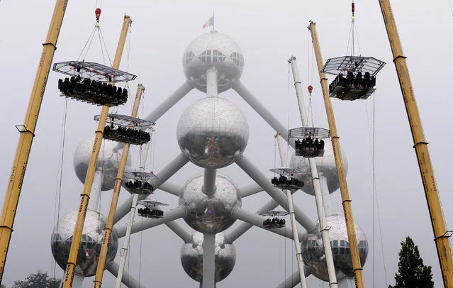 Ten tables, accommodating a total of 220 guests, are suspended from cranes at a height of 40 metres in front of the Atomium, a 102-metre (335 feet) high structure and its nine spheres, built  for the 1958  Brussels World's Fair, as part of the 10th anniversary of the event known as “Dinner in the Sky”, in Brussels, Belgium June 1, 2016. (Photo by Yves Herman/Reuters)