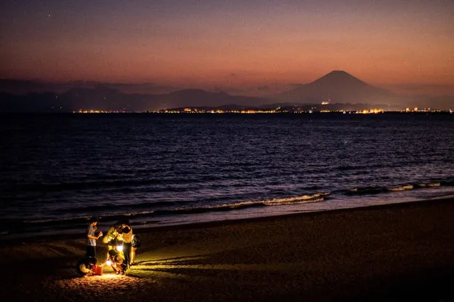 This picture taken on May 3, 2022 shows people gathering on the beach as Mount Fuji, Japan's highest mountain at 3,776 meters (12,388 feet), is seen from Shonan Kaigan Park in Fujisawa, south of Tokyo, during the “golden week” holiday. (Photo by Philip Fong/AFP Photo)