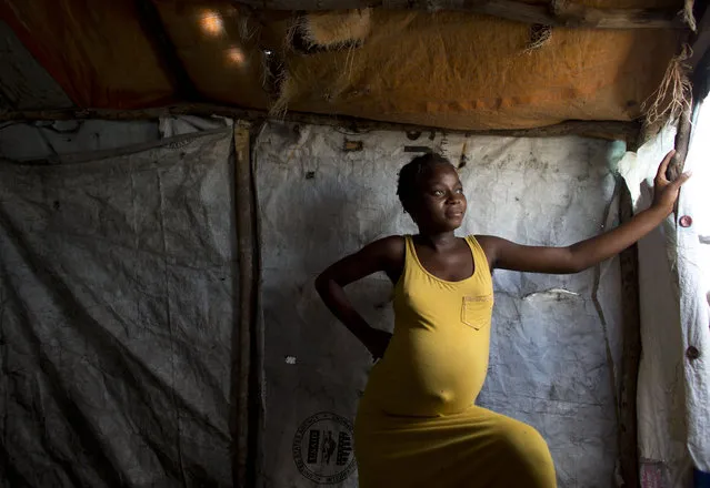 In this June 26, 2015 photo, Mirlande Senate, 17 and eight-months pregnant, stands in the small makeshift shelter where she lives alone in a Cite Soleil tent camp set up for people displaced by the 2010 earthquake in Port-au-Prince, Haiti. Orphaned years earlier and with no family to protect her, Senate said she has occasionally had to engage in prostitution to survive. (Photo by Rebecca Blackwell/AP Photo)