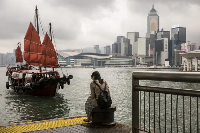 A junk boat sails in to dock as a woman sits on the pier in the central district of Hong Kong on May 15, 2019. (Photo by Isaac Lawrence/AFP Photo)