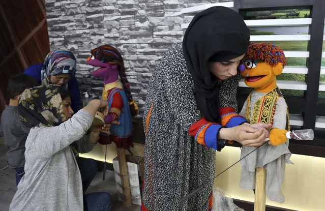 In this Monday, July 10, 2017 photo, Afghan puppeteers setting props for Sesame Street's new Afghan character, a 4-year-old Afghan puppet boy called Zeerak, right, and Zari, before a recoding a segment for Afghan version of Sesame Street called Baghch-e-Simsim for the sixth season of the program aired on TOLO a Local Television station in Kabul, Afghanistan. (Photo by Rahmat Gul/AP Photo)