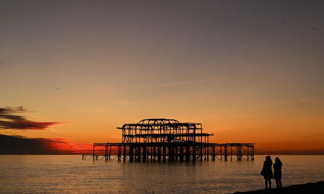 The sun sets on the horizon beyond the remains of the West Pier near Brighton beach, in Brighton, southern England, on January 20, 2020. (Photo by Glyn Kirk/AFP Photo)