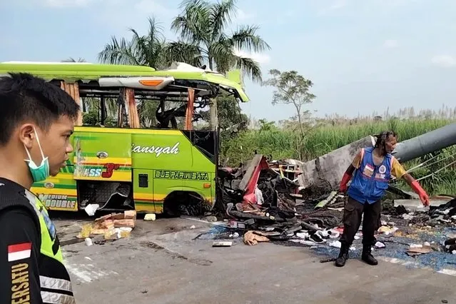 Rescuers inspect the wreckage of a tourist bus that crashed into a street sign on a highway in Mojokerto, East Java, Indonesia Monday, May 16, 2022. The accident killed and injured a number of people. (Photo by Misti Prihatini/AP Photo)