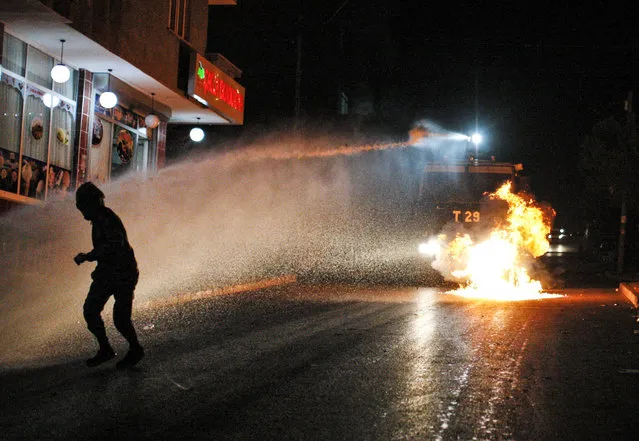 A left-wing protester runs to avoid water from a Turkish police water canon, after he threw a petrol bomb at it, during minor clashes between police and people protesting Turkey's operations against Kurdish militants. in Istanbul, early Sunday, August 16, 2015. There had been a sharp escalation of violence lately between Turkey's security forces and the Kurdistan Workers' Party, or PKK. and the collapse of a two-year peace process with the rebels. Dozens of people, mostly Turkish soldiers, have died since July in the renewed violence. (Photo by Cagdas Erdogan/AP Photo)