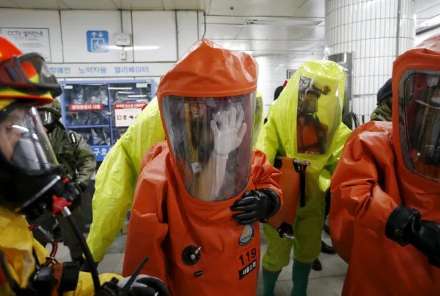 A firefighter wipes his protective gear from inside to remove moisture as he and others take part in an anti-terror drill in Seoul, South Korea, August 19, 2015. South Korea on Wednesday (August 19) staged a nationwide civil defence drill, called the annual Ulchi Exercise, where they hope to prepare the general public for all possible emergencies. (Photo by Kim Hong-Ji/Reuters)